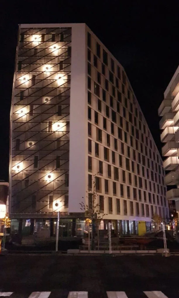 Opplyst strekkmetallfasade på Scandic Portalen i Lillestrøm om kvelden